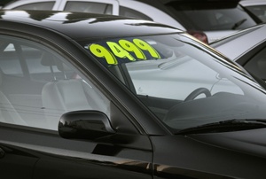 A black car with a price sticker on the windshield.