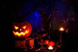 A jack-o'-lantern and assorted Halloween decorations in a darkly-lit room.