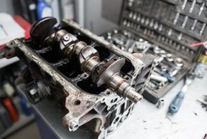 A crankshaft sitting on a workbench surrounded by tools.