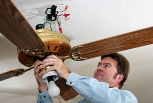 A man wiring a ceiling fan.