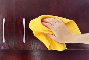 a hand cleaning a kitchen cupboard.