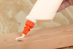 squeezing wood glue onto a piece of wood
