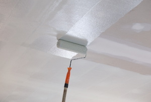 rolling primer onto a ceiling