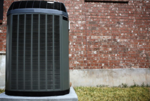 black air conditioning unit next to a brick wall outside .