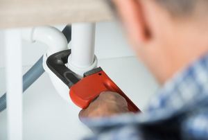 A plumber working on a sink drain pipe.