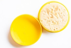 an open circular yellow container of soldering flux gel