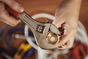 Someone holding a wrench around a pipe.