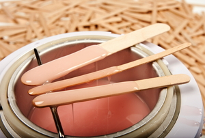 Three waxing sticks covered in dripping hot body wax.