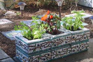 A small planter made of cinder blocks covered with mosaic tiles. 