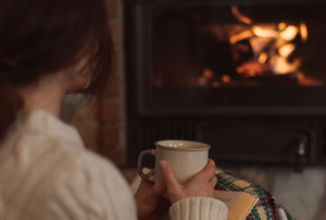 woman with cup in front of gas fireplace with low flame