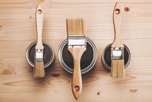 Paint brushes and cans of paint on wood
