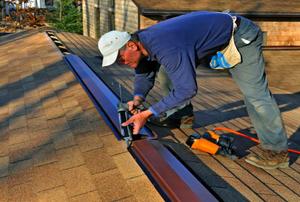 A worker laying caulk along a ridge vent.