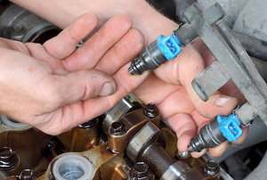 a hand touching the fuel injector on an engine