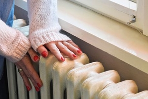 Person's hands on a wall radiator