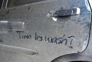A dirty car with the words "time to wash?" written in the dust. 
