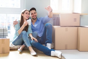 A couple on moving day sitting on the floor surrounded by boxes.