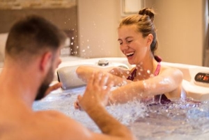 man and woman splashing happily in hot tub
