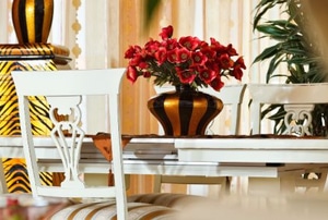 flowers on a table with colorful vases and elaborate chairs