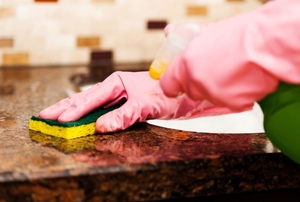 pink gloved hands cleaning granite