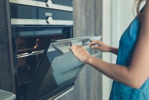 A woman opening up an oven door.
