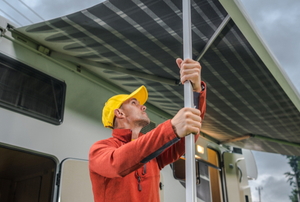 man holding pole supporting rv awning