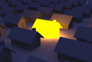 A row of dark houses with one glowing yellow. 