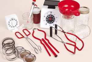 A collection of supplies for canning, including tongs and jar lids.