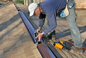 Man caulking a roof ridge vent