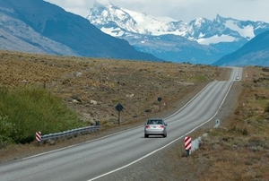 car driving on a highway toward snowy mountains