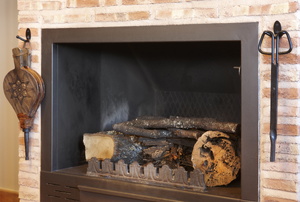 A brick fireplace with tools on either side of it.