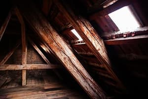The corner of an old attic with windows on the near wall.