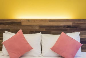 A rustic wood headboard with white and pink pillows.