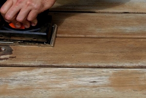 Someone sanding the surface of a deck.