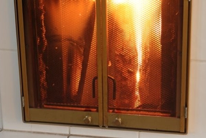 fire in a fireplace behind brass-framed glass doors