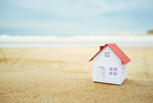 A small white house on a sandy beach.