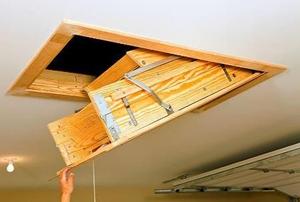 A hand pulling down an access door in a garage.