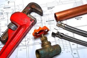 A wrench and some pipes laying on top of blueprints.