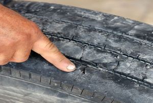 A man points to dry rot on a tire.