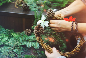 Friends DIYing a Christmas wreath together.