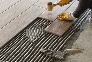 hands laying long tiles on mortar with tools