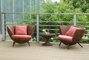 Two outdoor wicker chairs covered with seat cushions.