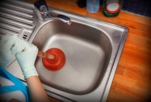 Using a sink plunger on a clogged drain.