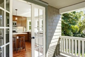 double doors leading into a wood-floored kitchen from a sunny porch