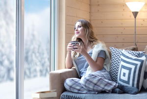 A woman looking out the window with a cup of coffee. 