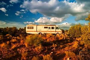 A motor home parked in the desert under a fantastic sky.