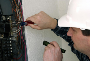man working on wiring in a wiring control panel