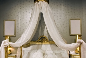 Bed with gold frame and cream canopy and bed cover
