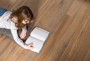 A woman reading a book on a floor. 