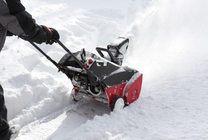 Man removing snow after storm with a snowblower.