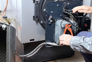 person working on fixing back of oil burner